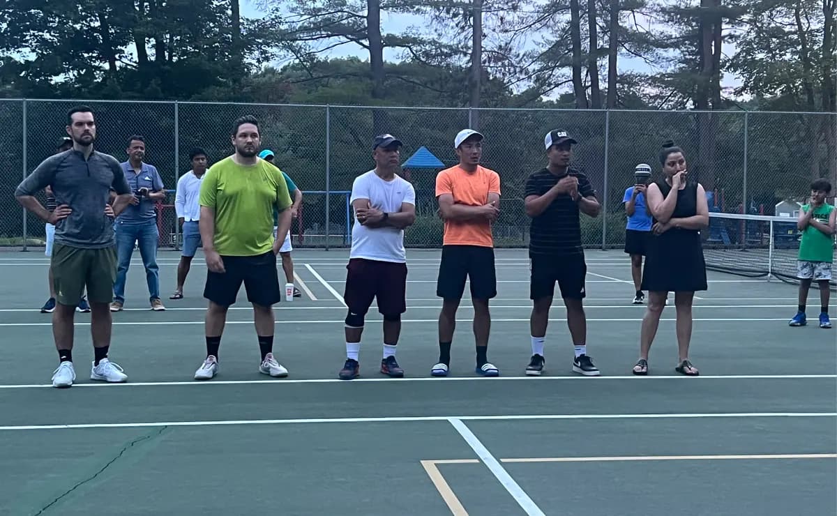 A group of UDTA players and volunteers stand together courtside.