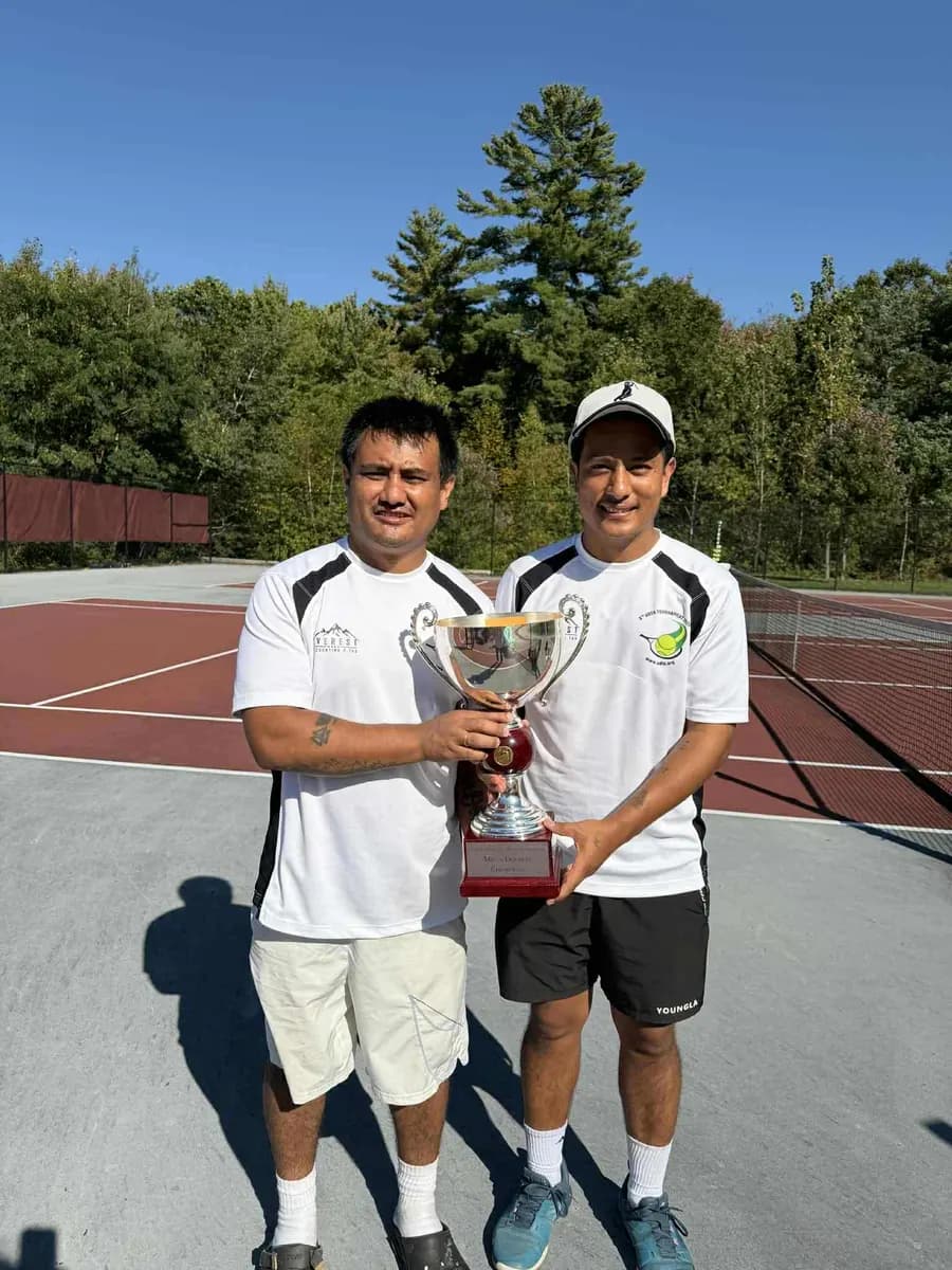 Two men hold the Men's Doubles Champions trophy together at the net.