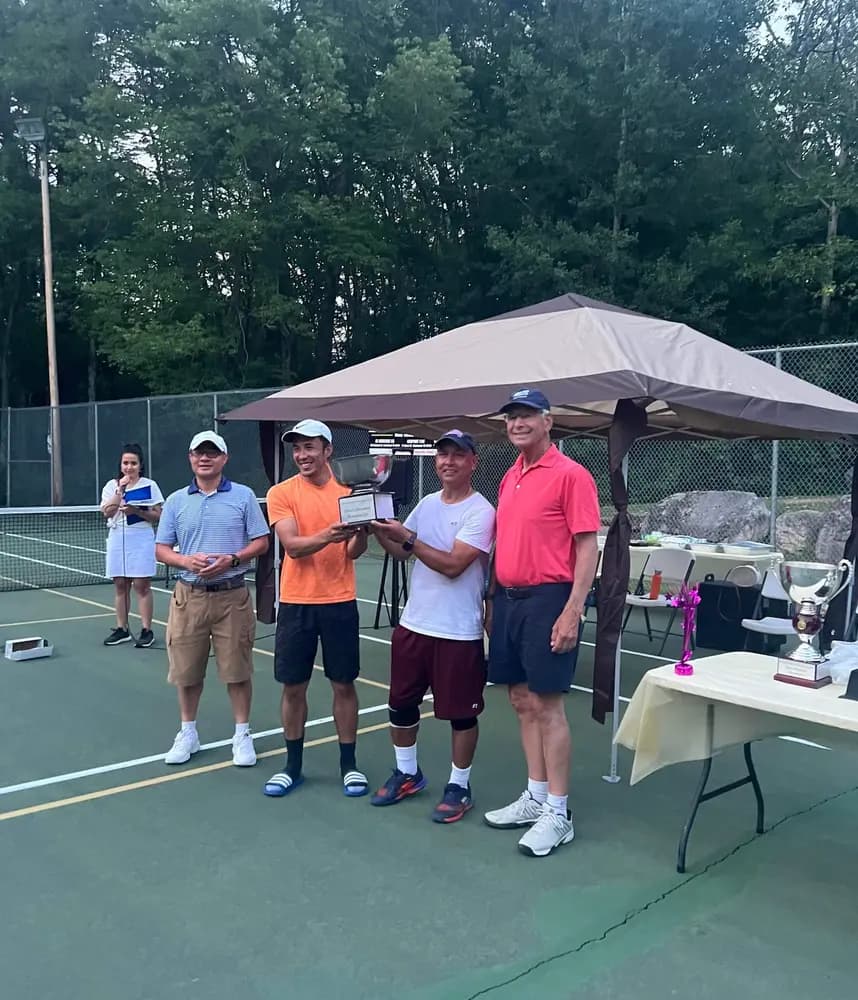 Four men stand together holding a trophy at a UDTA tournament awards presentation.